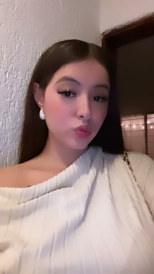 Woman with long dark hair in a cream off-shoulder sweater, close to the camera